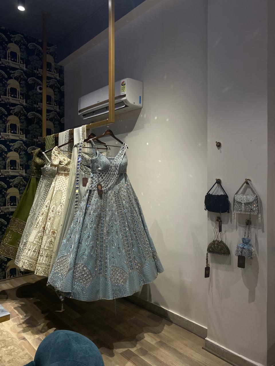 Dresses hanging on a rack with bags displayed on the wall in a store setting
