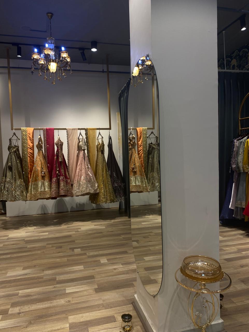 Display of traditional dresses in a store with a large mirror reflecting the dresses