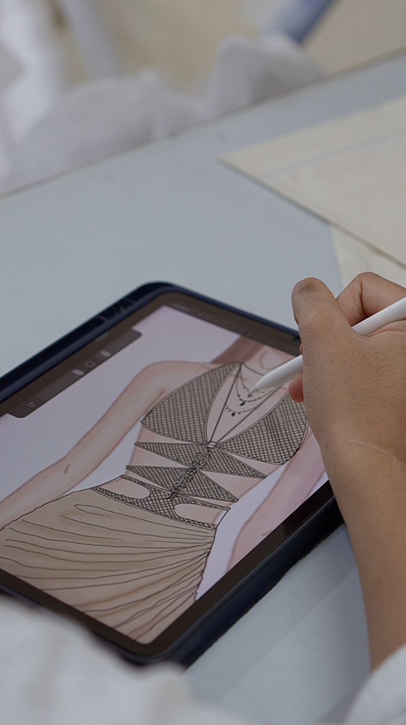 Person using a stylus on a digital tablet displaying a fashion illustration.