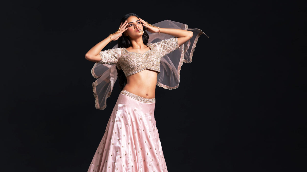 Woman in a traditional outfit with sheer sleeves against a black background